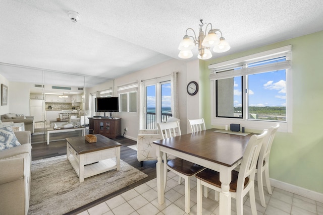 dining area with a textured ceiling, light tile flooring, and a chandelier