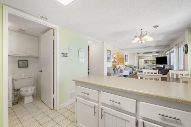 kitchen featuring a chandelier, white cabinetry, a textured ceiling, and light tile flooring