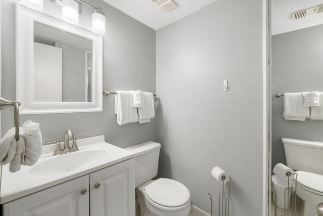 bathroom with a textured ceiling, vanity, and toilet