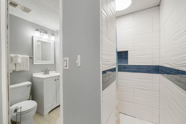 bathroom featuring a textured ceiling, vanity, tile floors, and toilet