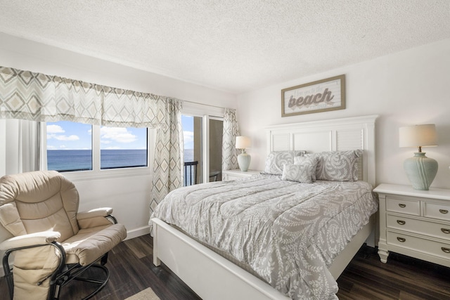 bedroom featuring a water view, dark hardwood / wood-style floors, and a textured ceiling