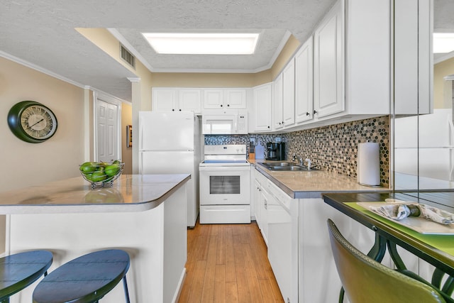 kitchen featuring a kitchen breakfast bar, white cabinets, white appliances, backsplash, and a textured ceiling