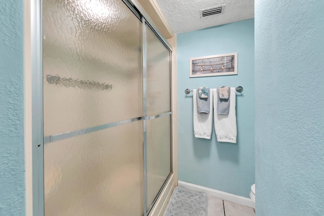 bathroom with a textured ceiling, an enclosed shower, tile floors, and toilet