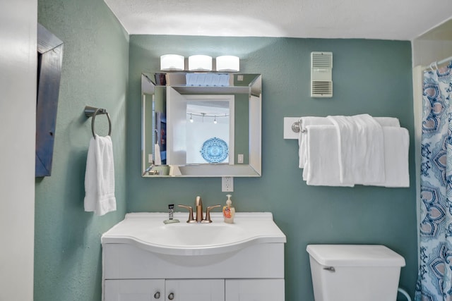 bathroom with a textured ceiling, vanity, and toilet