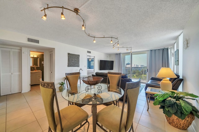 dining room with rail lighting, floor to ceiling windows, a textured ceiling, and light tile floors