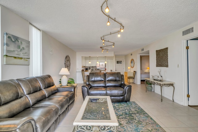 tiled living room featuring a textured ceiling and track lighting