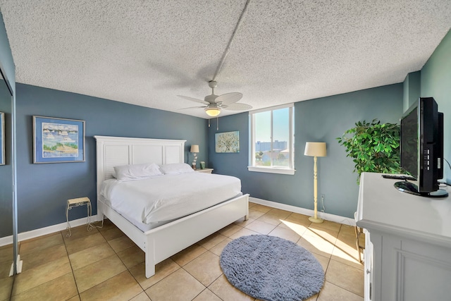 bedroom featuring ceiling fan, light tile floors, and a textured ceiling