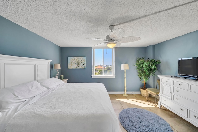 tiled bedroom featuring ceiling fan and a textured ceiling