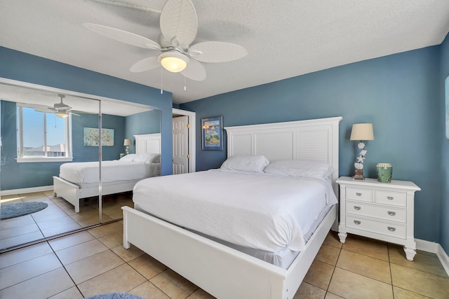 bedroom featuring a closet, ceiling fan, light tile floors, and a textured ceiling