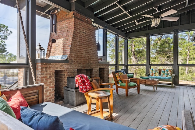 sunroom / solarium with vaulted ceiling, ceiling fan, and a brick fireplace