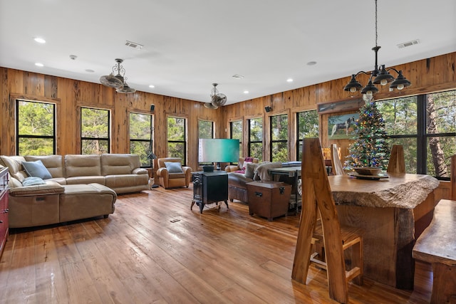 living room with wood walls, light hardwood / wood-style floors, and a chandelier