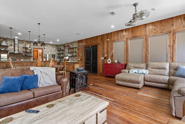 living room featuring hardwood / wood-style floors, wooden walls, and a wood stove