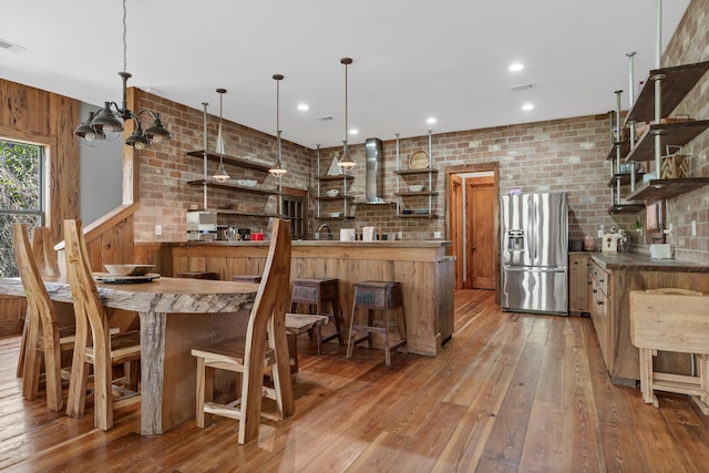 dining area featuring sink, dark hardwood / wood-style flooring, brick wall, and a chandelier