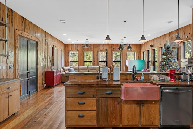 kitchen with a wealth of natural light, wood walls, light hardwood / wood-style floors, and stainless steel dishwasher