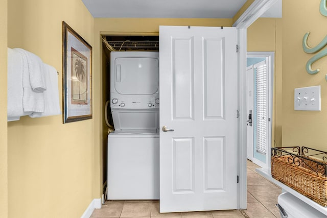 laundry area with laundry area, baseboards, stacked washing maching and dryer, and light tile patterned floors