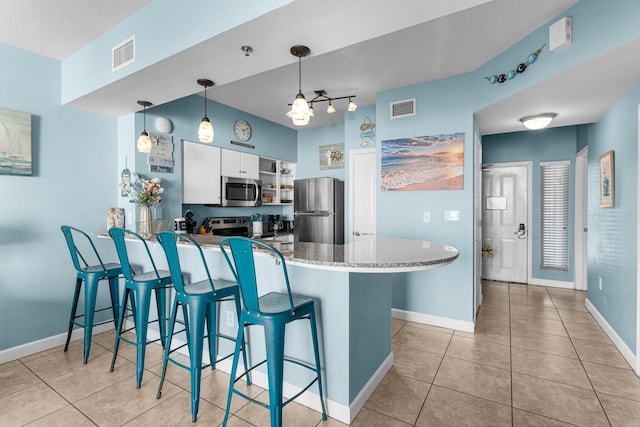 kitchen with stainless steel appliances, a peninsula, visible vents, and a kitchen breakfast bar