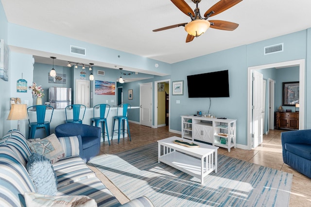 living room featuring a ceiling fan, tile patterned flooring, visible vents, and baseboards