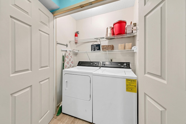 clothes washing area with light hardwood / wood-style flooring and washer and dryer