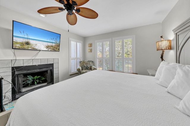 bedroom featuring a tiled fireplace and ceiling fan