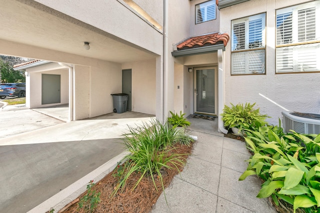 view of exterior entry featuring central AC and a patio area