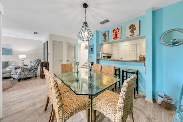 dining area with light hardwood / wood-style flooring and an inviting chandelier