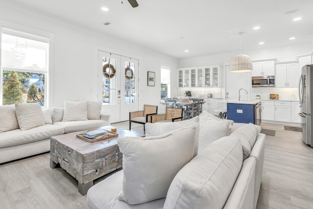 living room with french doors, ceiling fan, light hardwood / wood-style floors, and sink