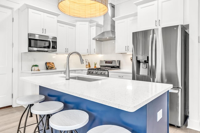 kitchen with wall chimney exhaust hood, tasteful backsplash, light wood-type flooring, stainless steel appliances, and a kitchen breakfast bar