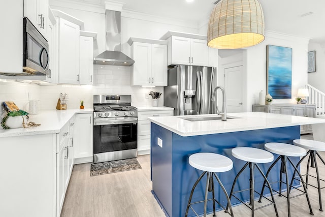 kitchen with appliances with stainless steel finishes, a center island with sink, backsplash, and wall chimney exhaust hood