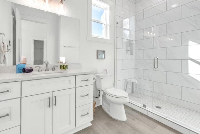 bathroom featuring wood-type flooring, vanity, toilet, and walk in shower