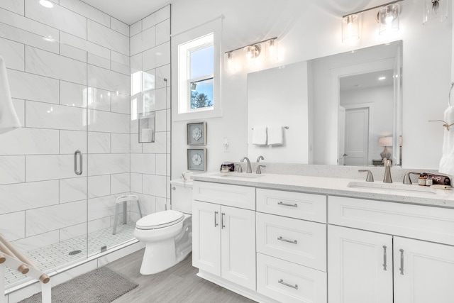 bathroom with a shower with door, double vanity, and toilet