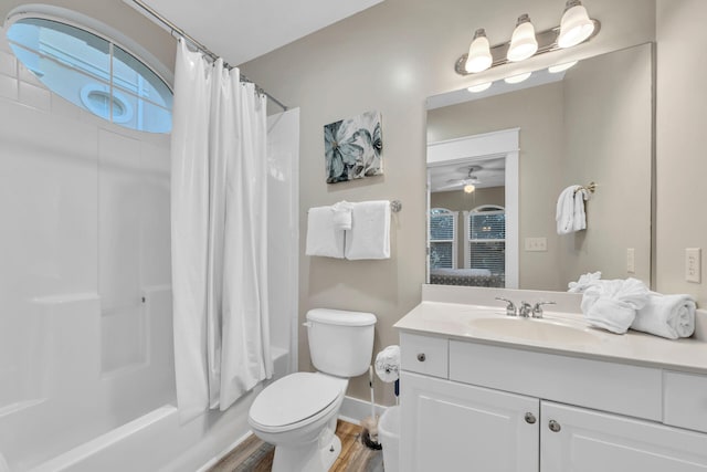 full bathroom with ceiling fan, vanity with extensive cabinet space, hardwood / wood-style floors, shower / bath combo, and toilet