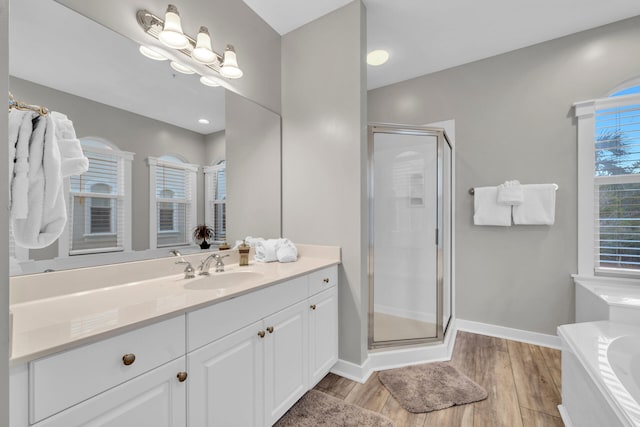 bathroom with hardwood / wood-style floors, independent shower and bath, and vanity