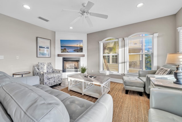 living room featuring a fireplace, hardwood / wood-style floors, and ceiling fan