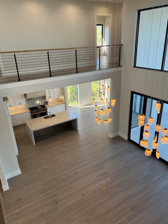 unfurnished living room with wood-type flooring, sink, and a towering ceiling