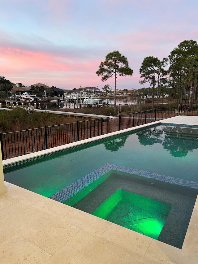 pool at dusk with an in ground hot tub