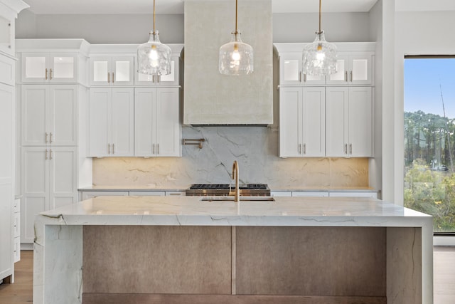 kitchen with light stone countertops, white cabinetry, and hanging light fixtures