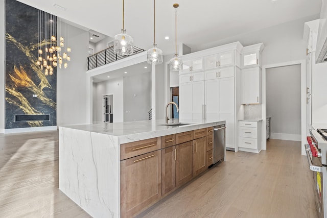 kitchen featuring light stone countertops, a spacious island, sink, light hardwood / wood-style flooring, and white cabinetry