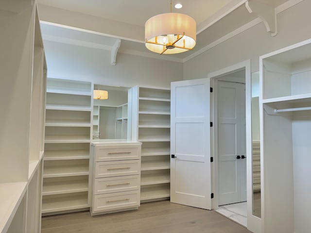 walk in closet featuring light hardwood / wood-style floors and an inviting chandelier