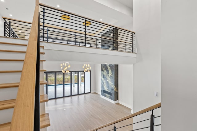 stairway with hardwood / wood-style flooring, a towering ceiling, and an inviting chandelier