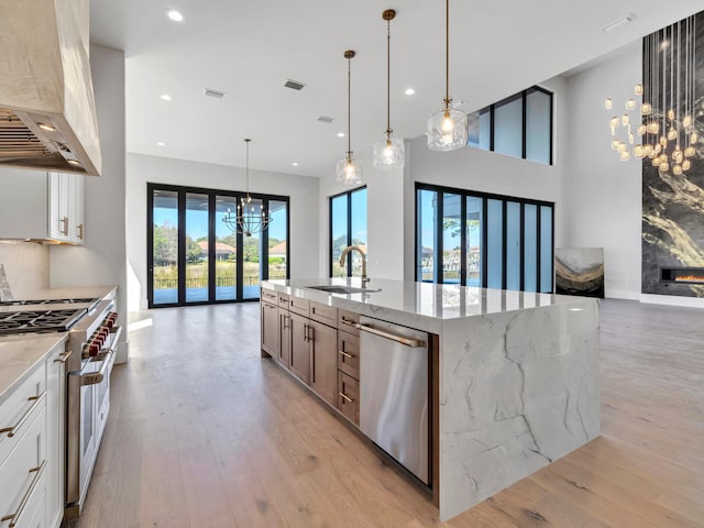 330 Kelly Plantation Dr, Destin, FL 32541 - kitchen with wall chimney range hood, a chandelier, appliances with stainless steel finishes, a sink, and light wood finished floors