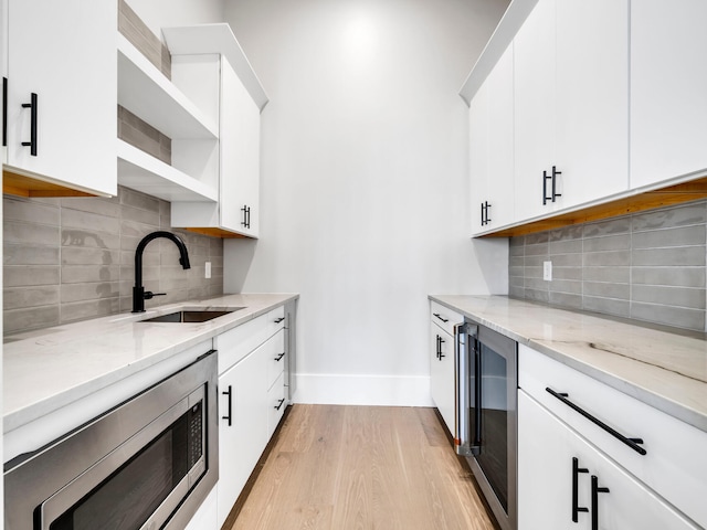 330 Kelly Plantation Dr, Destin, FL 32541 - kitchen featuring stainless steel microwave, beverage cooler, light wood-style floors, a sink, and open shelves