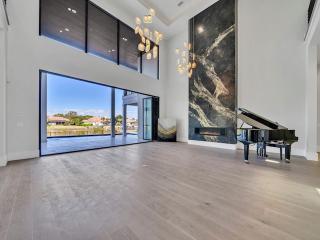 330 Kelly Plantation Dr, Destin, FL 32541 - unfurnished living room featuring a towering ceiling, wood finished floors, a chandelier, and baseboards