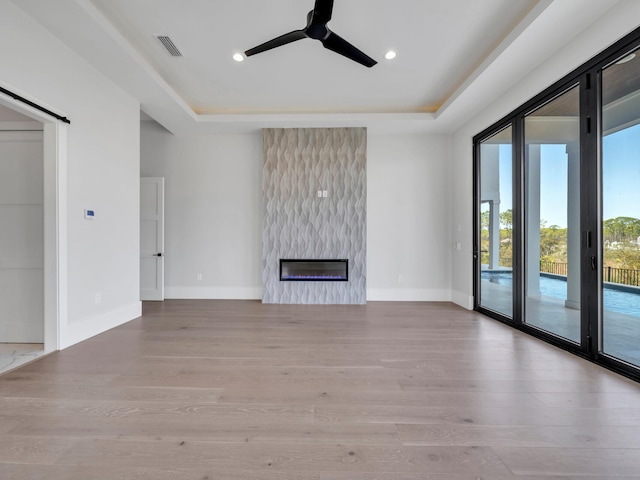 330 Kelly Plantation Dr, Destin, FL 32541 - unfurnished living room featuring ceiling fan, a raised ceiling, wood finished floors, baseboards, and a high end fireplace