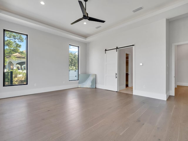 330 Kelly Plantation Dr, Destin, FL 32541 - unfurnished bedroom featuring a barn door, wood finished floors, recessed lighting, a raised ceiling, and baseboards