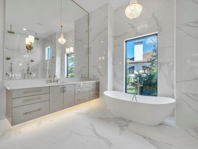 330 Kelly Plantation Dr, Destin, FL 32541 - bathroom featuring marble tiled floors, vanity, stone wall, a soaking tub, and a chandelier