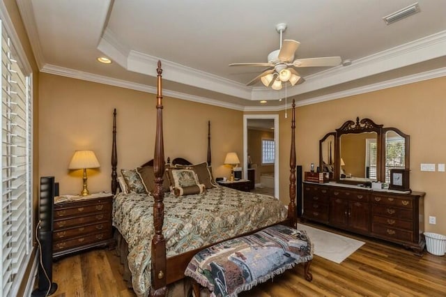 bedroom with ornamental molding, dark hardwood / wood-style flooring, ceiling fan, and a raised ceiling