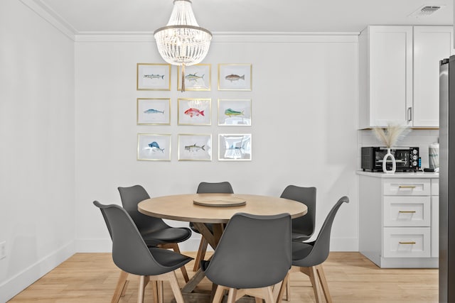 dining area featuring a notable chandelier, light hardwood / wood-style floors, and crown molding