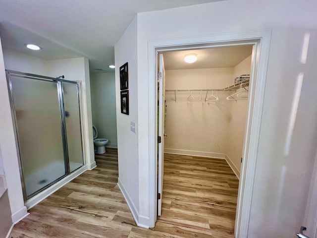 bathroom with hardwood / wood-style flooring, toilet, and walk in shower