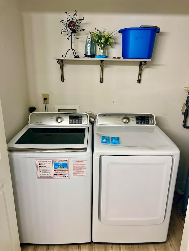 laundry room with separate washer and dryer and light hardwood / wood-style flooring