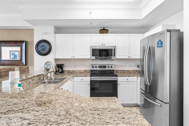 kitchen with kitchen peninsula, appliances with stainless steel finishes, light stone countertops, sink, and white cabinetry